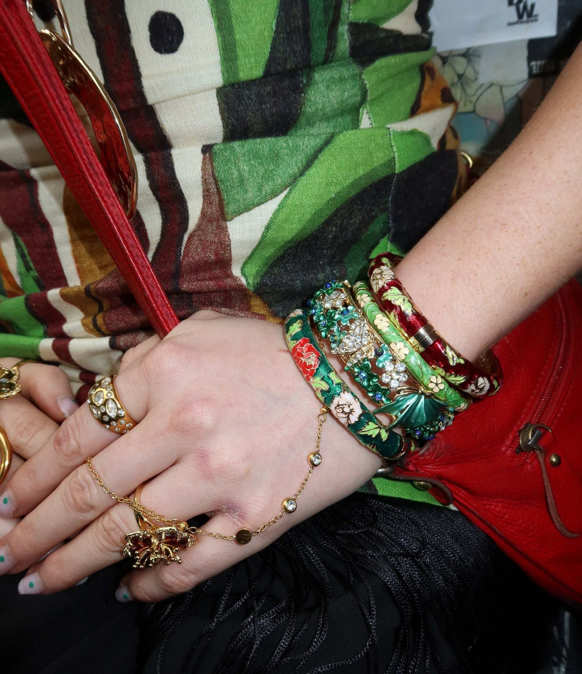 AURORA BANGLE IN BLUE, a stack of glossy green enamel bangles with multicoloured floral details and gold-tone accents