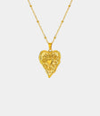 Gold-tone GRACE NECKLACE with a fine chain and ornate heart-shaped pendant featuring a small raised heart detail.