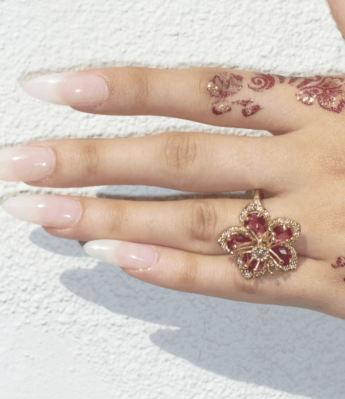 Lovela Ring in Red, gold-tone flower ring with deep red petal details and sparkling accents on an adjustable band