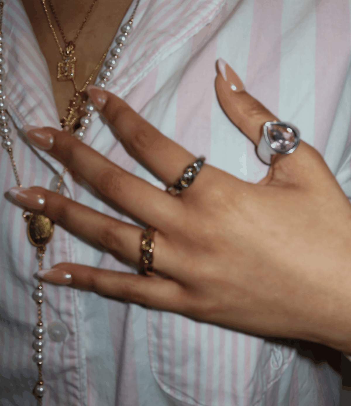 Olive Ring with a dark beaded band shown alongside gold and silver rings on a hand with nude nails
