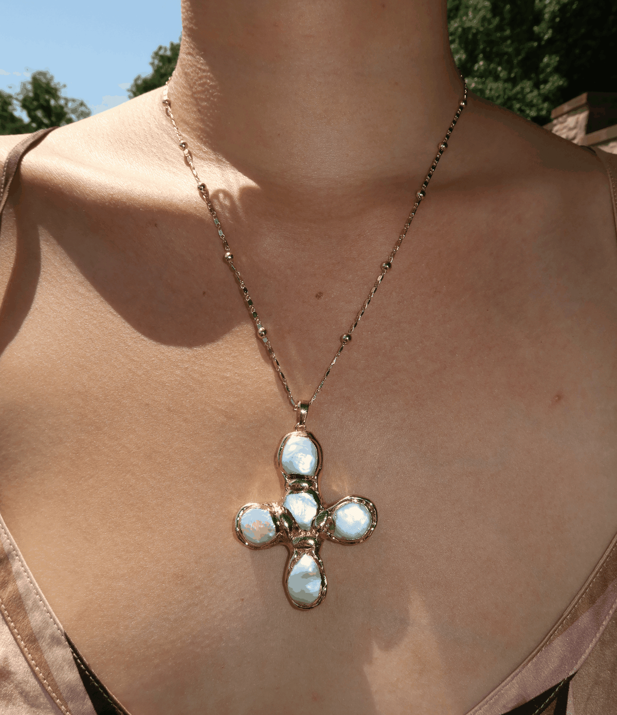 Olympia Necklace in a fine gold-tone chain with a large cross-shaped pendant set with pale blue stones