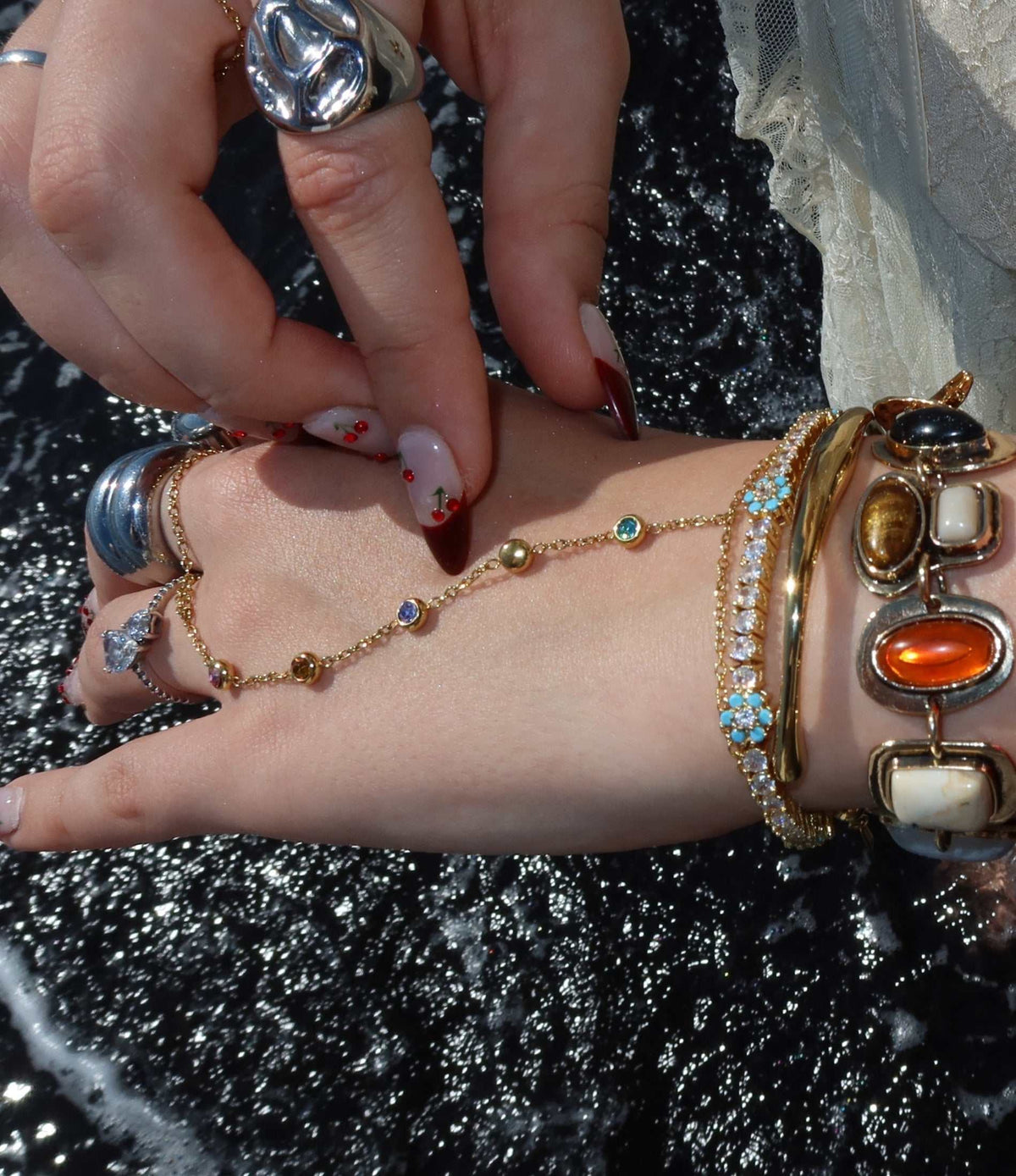 ADA BRACELET hand-chain in gold-tone metal with a delicate linked chain and small multicolour gemstone accents, connecting wrist to finger ring.