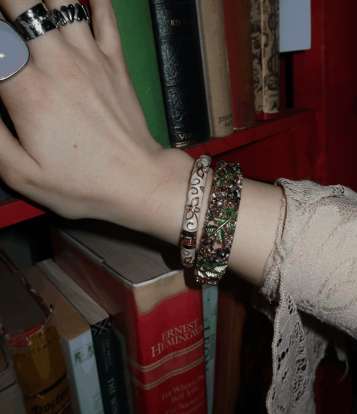 LA VIE EN ROSE BANGLE with ornate silver-toned metal, green and red floral detailing, worn beside a cream bangle
