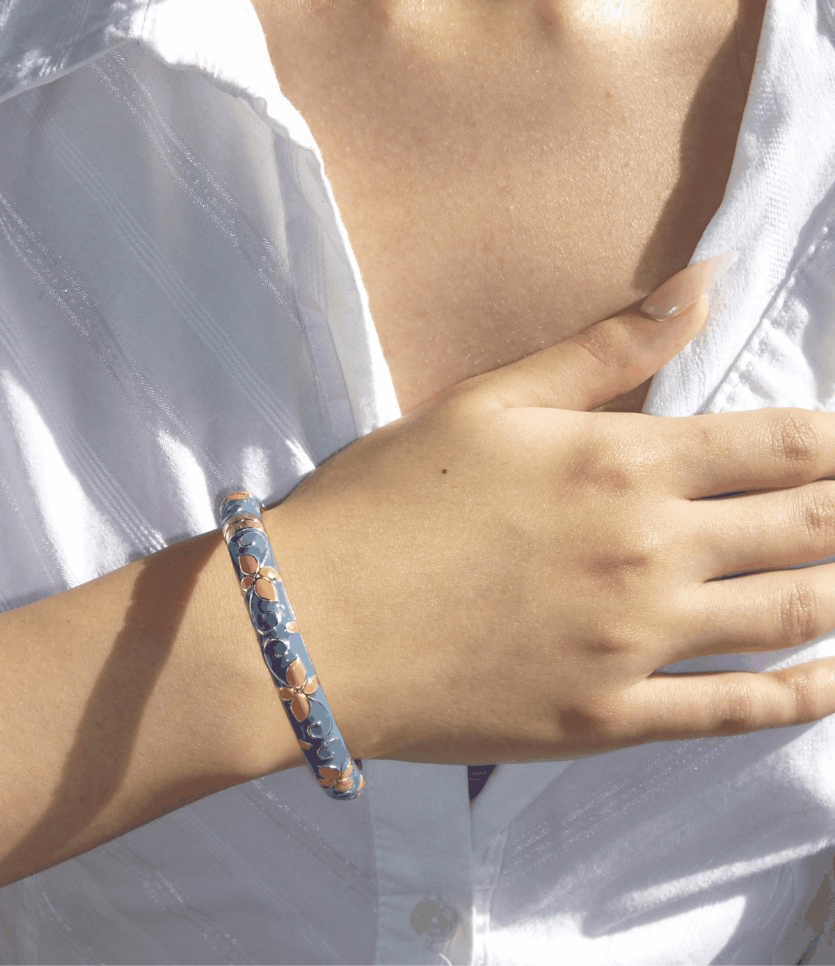 PRIMAVERA BANGLE IN APRICOT BLUE, a slim enamel bangle with soft blue and warm apricot floral detailing