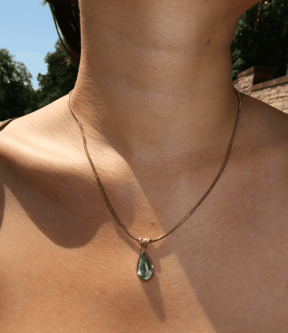 WATER DROP NECKLACE with a fine gold-tone chain and a blue-green teardrop pendant in a gold-tone setting.
